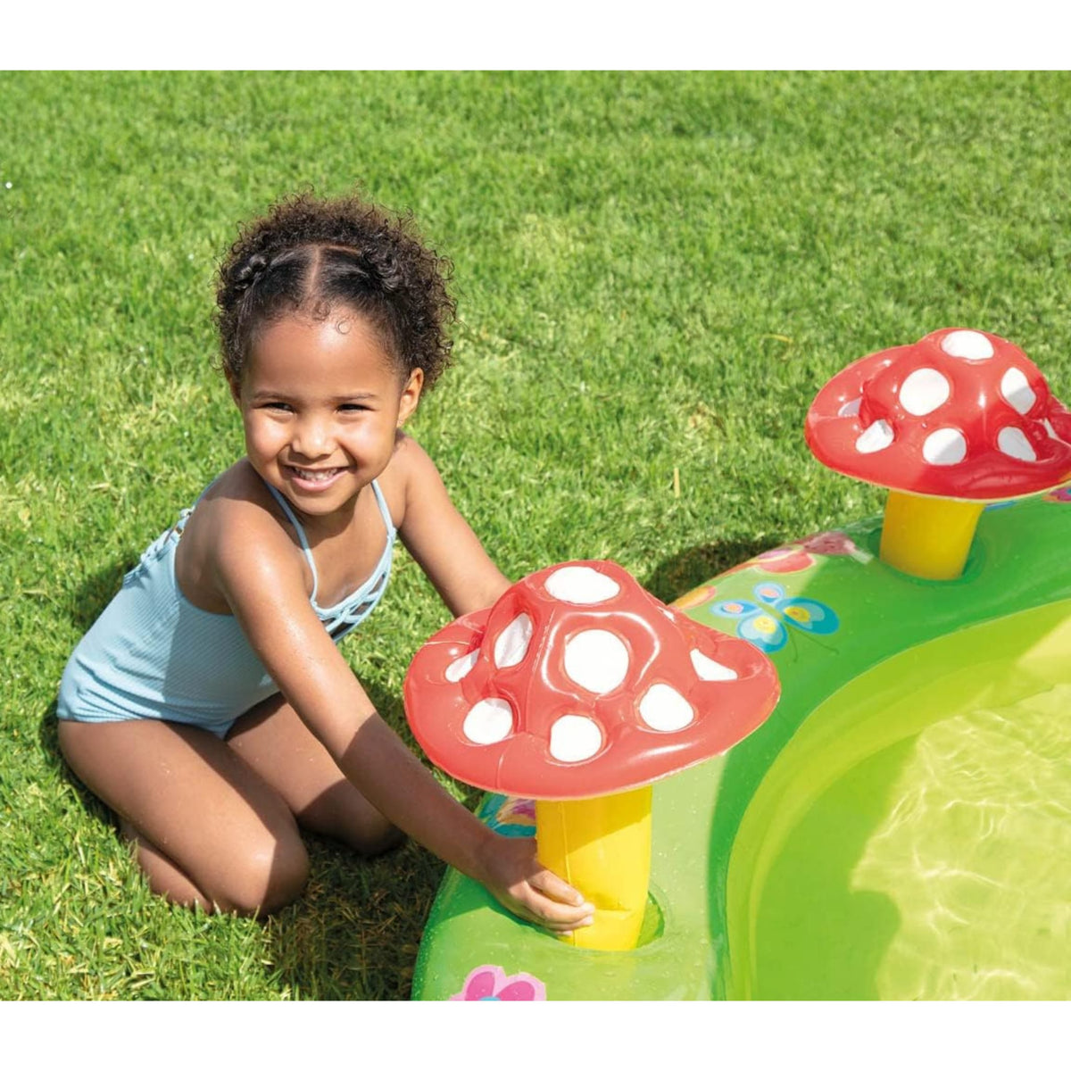Child playing with a mushroom-shaped toy in a pool on a sunny day