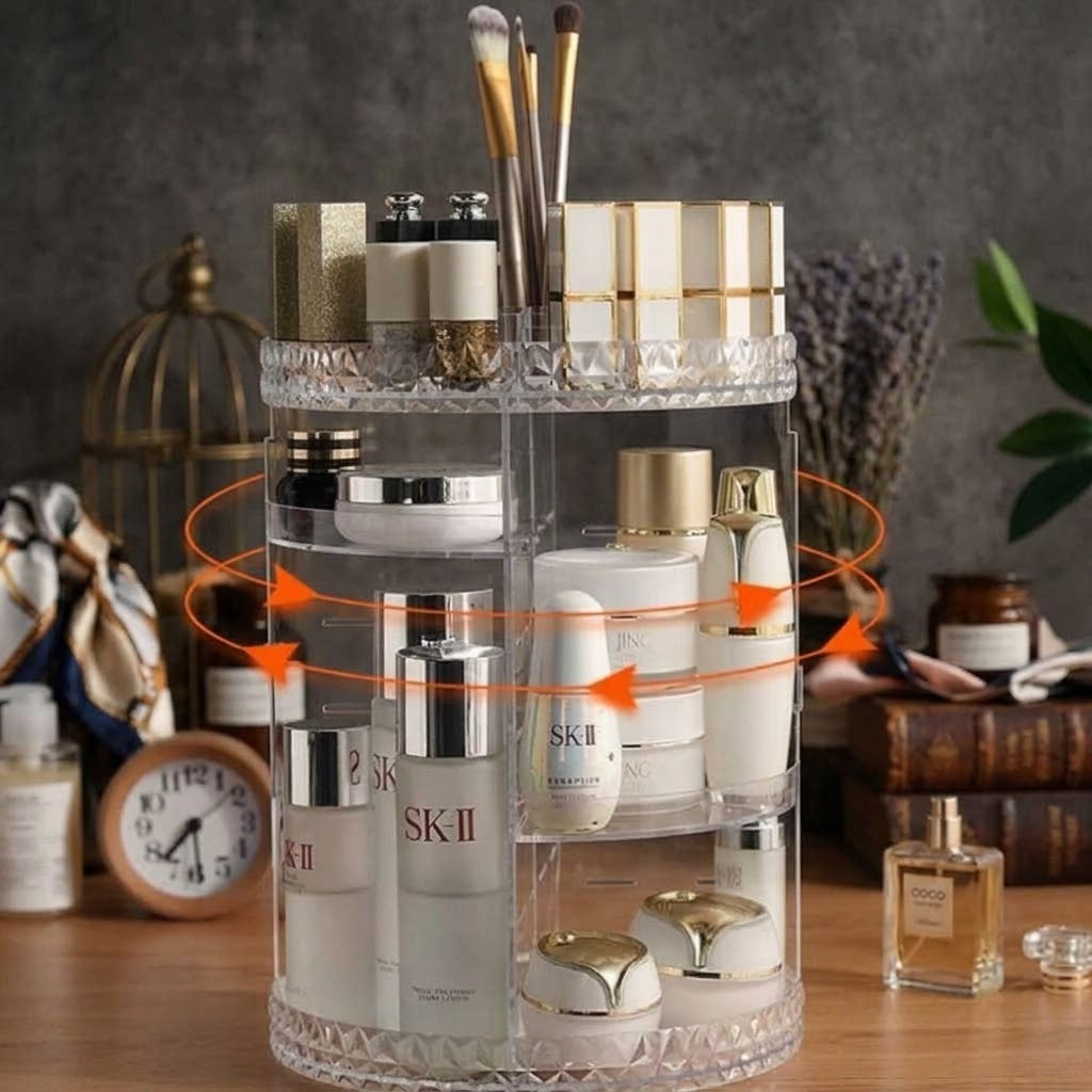 A clear acrylic rotating cosmetic organizer filled with skincare and makeup products, shown on a tabletop in a styled room setting with decorative props and orange rotation arrows overlaid to demonstrate use.