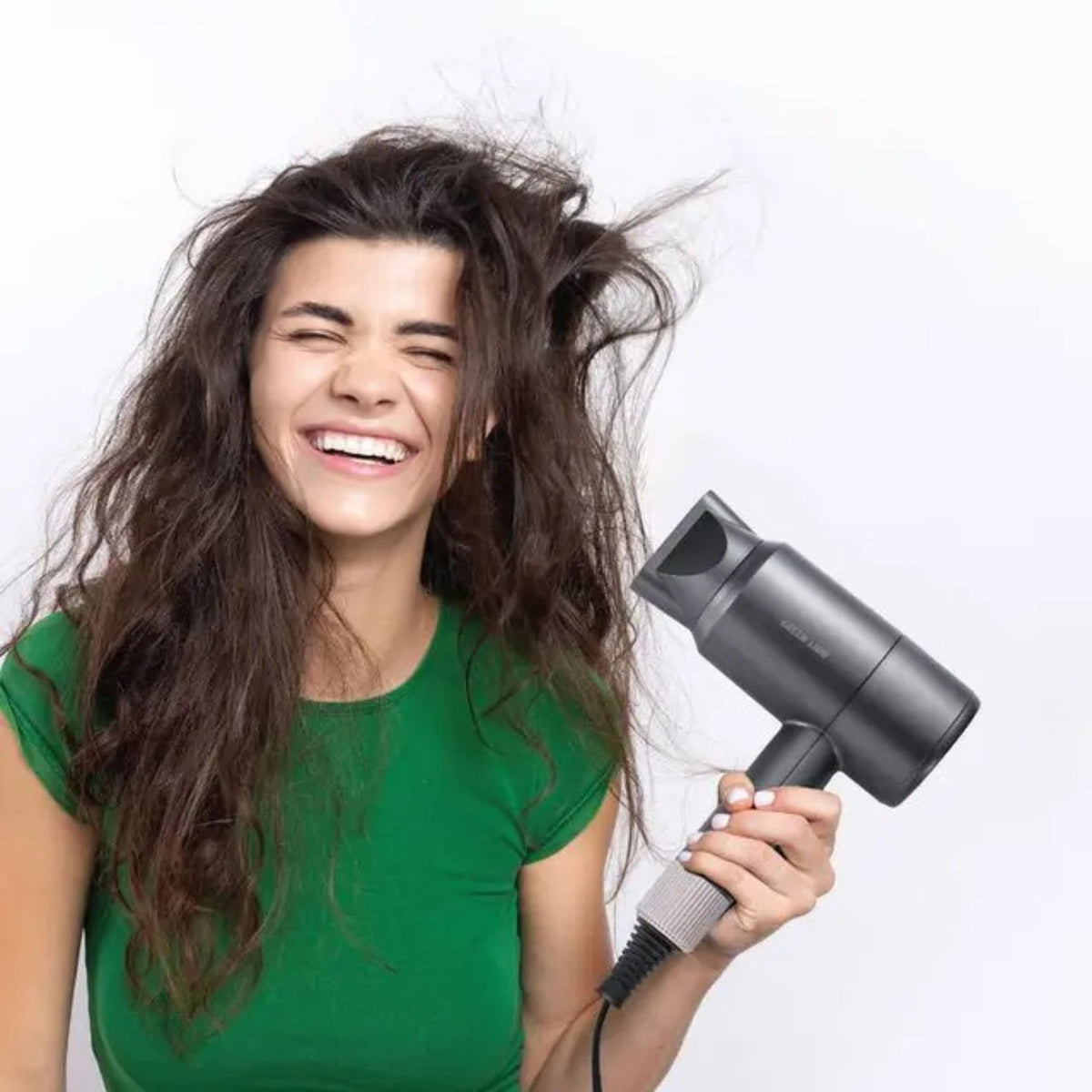 Woman with long hair using a hair dryer on a white background