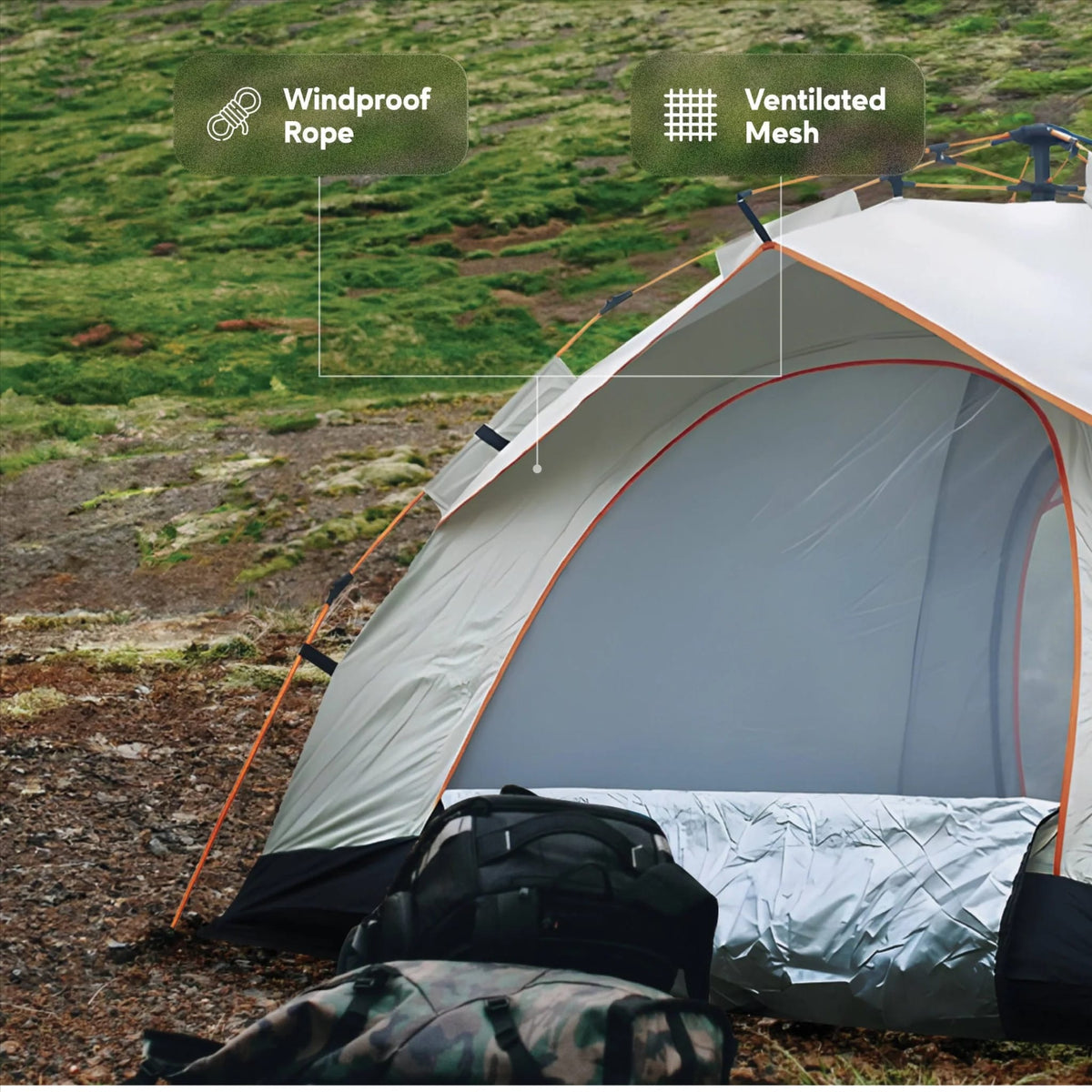 A gray and white camping tent pitched outdoors on a grassy, rocky hillside. Two callout labels point to features of the tent: 'Windproof Rope' near the guyline area and 'Ventilated Mesh' near the front door.