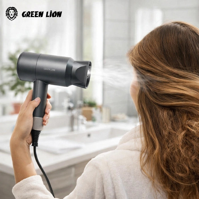 A woman in a white robe uses a black Green Lion hair dryer with steam function in a bright bathroom. The brand logo 'GREEN LION' is visible in the top left corner.