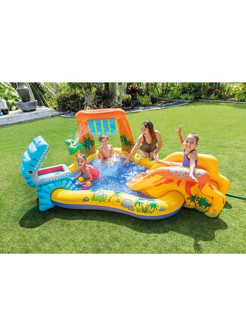 Children playing in an inflatable pool with a dinosaur design on a grassy area.