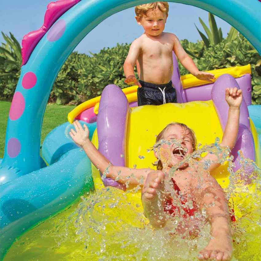 Two children playing on a colorful inflatable water slide with a garden background.