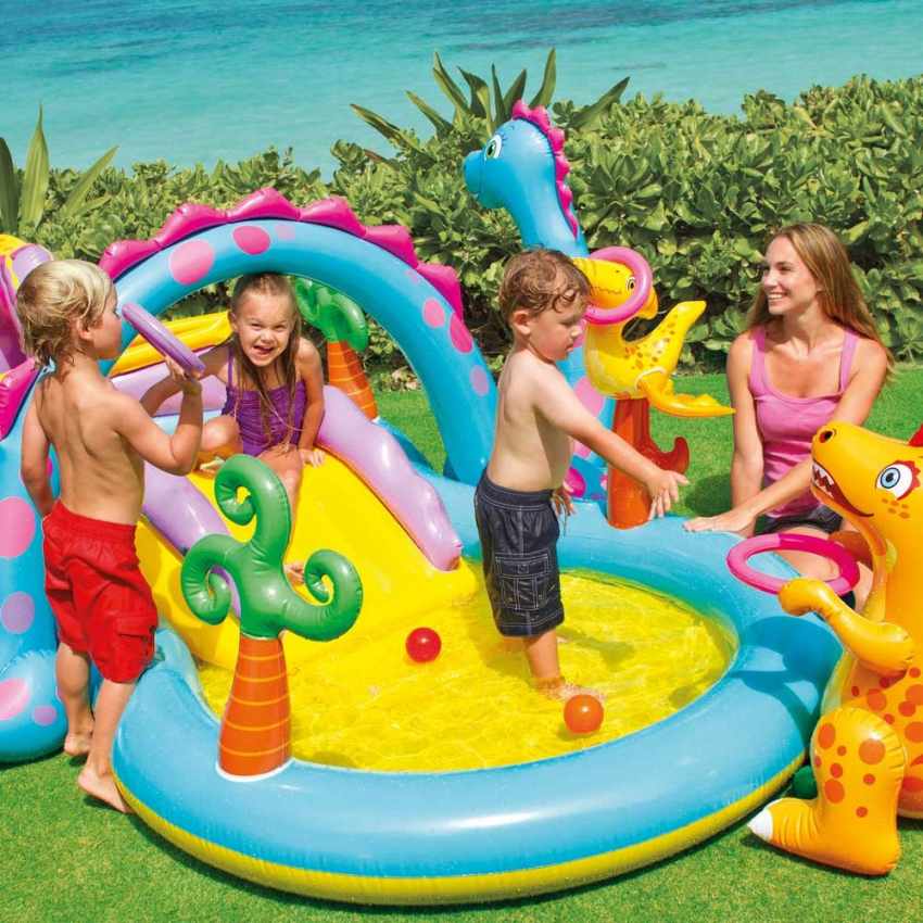 Children playing in a colorful inflatable water park with a woman supervising.