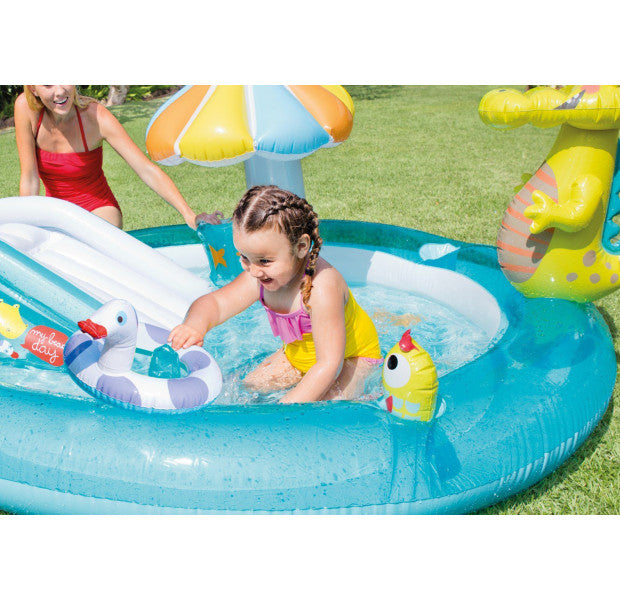 Child playing in an inflatable pool with toys on a grassy area
