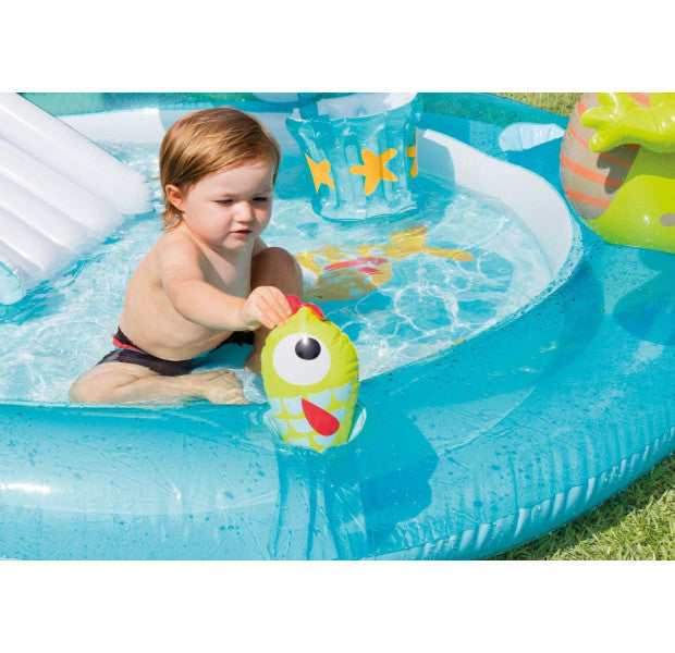 Child playing with a toy in an inflatable pool on a grassy area