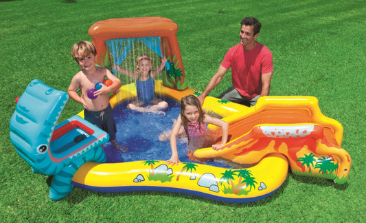 Children playing in an inflatable water park on a grassy area with a man supervising.