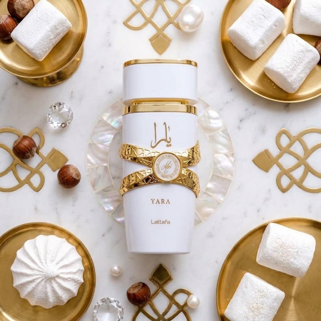 Lattafa Yara white and gold perfume bottle displayed on a marble surface with gold trays, white sweets, pearls, and elegant decorative accents.