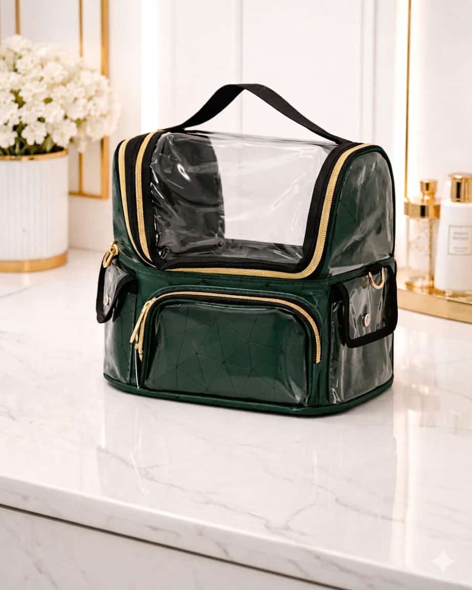 Green transparent cosmetic bag with gold zippers on a marble surface.
