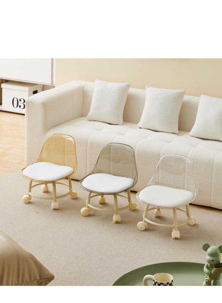 Three modern rolling accent chairs with white seats and light wood frames are arranged in front of a cream-colored sofa in a bright, minimalist living room.